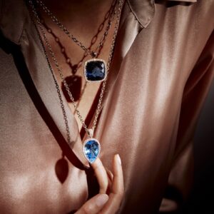 Nahaufnahme einer Frau mit farbigen Edelstein- und Diamantketten aus der Positano-Kollektion, aufgenommen im Dekolleté-Bereich – Schmuck mit italienischer Raffinesse und modernem Design.